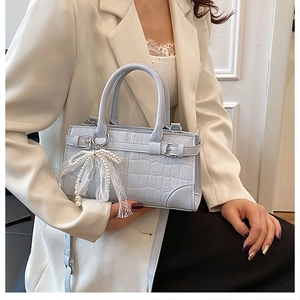 Light blue faux crocodile handbag with pearl lace bow detail worn by a model