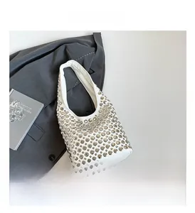 Detailansicht der weißen PU-Leder Handtasche mit silbernen Nieten auf grauem Blazer