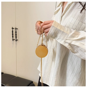 Detail of a round gold evening clutch bag with fine metal chain and top bead clasp