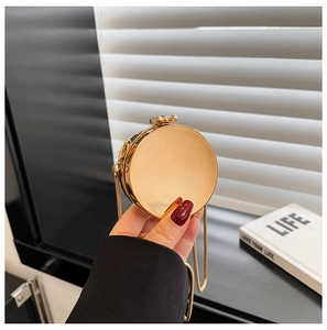 Close-up of golden circular acrylic evening clutch bag with sleek metal chain and clasp