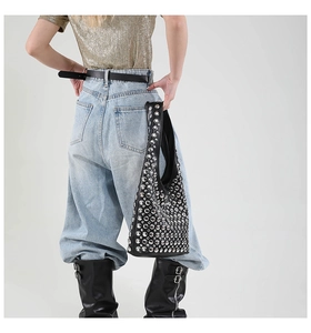 Detail of black leather hobo bag featuring silver rivets and studs on a model
