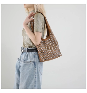 Detail of silver rivets on a brown leather crescent shoulder bag with punk aesthetic