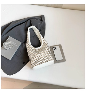 Detailed close-up of white PU leather handbag with silver metallic rivet studs