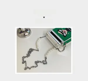 Detail of green crossbody bag with cartoon embossed motif and pearl chain strap