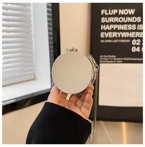 Detail of a mini round silver mirror acrylic bag with a sleek metallic chain strap