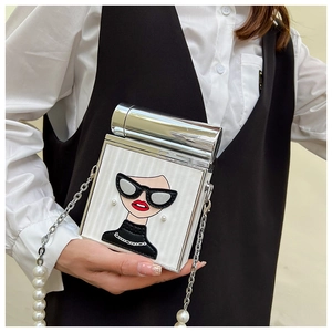 Detail of white chain bag with pearl strap and stylish figure print on shirt background