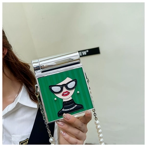 Detail of green handbag showing 3D cartoon figure with sunglasses and pearl chain strap
