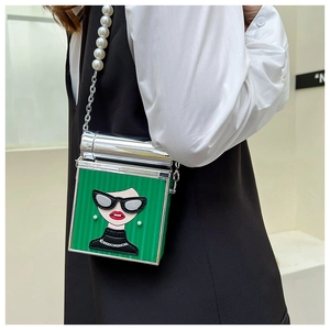 Detail of green mini box bag with fashion illustration and pearl chain strap on model