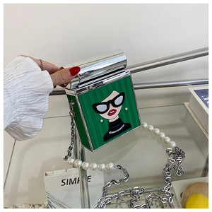 Close-up of bright green cartoon print crossbody bag with pearl and silver chain strap