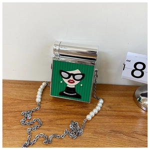 Detail of green square bag featuring cartoon girl embroidery and pearl chain strap