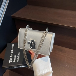 Silver metallic mini chain bag with unique keyhole lock held against a staircase