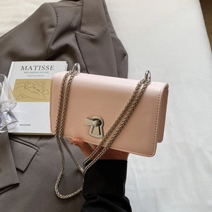Light pink leather chain crossbody bag with silver lock held by a model