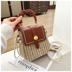 Detail of woven patchwork handbag featuring brown leather flap and pleated handle design