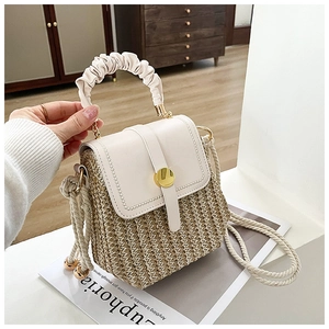 Detail of woven straw handbag with white leather handle and gold round buckle detail
