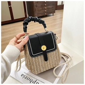 Detail of woven straw handbag with black leather flap, gold buckle and rope strap