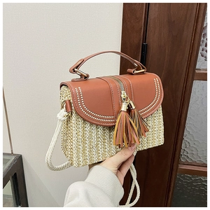 Detail of straw woven bag with brown leather flap and stylish dual leather tassels