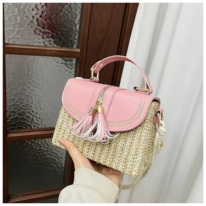 Detail of straw handbag with pink leather flap, matching tassels and cotton rope strap