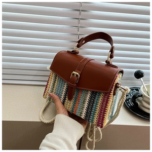 Detail of colorful woven straw bag with brown leather strap and gold hardware accents