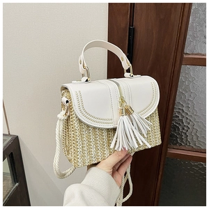 Detail of handmade straw bag with cream leather flap, white tassels, and woven rope strap