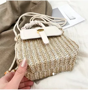 Dettaglio della trama in paglia intrecciata e della patta in pelle crema della borsa