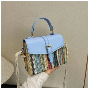 Detail of colorful woven straw bag with blue leather flap and thick white rope strap