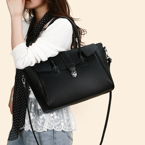 Detail of black pebbled leather tote bag featuring elegant silver metal clasp closure