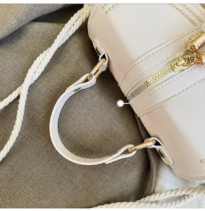 Close-up of cream woven bag showing gold hardware, star embroidery, and comfort handles