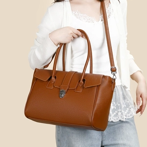 Close-up of brown lychee grain leather tote bag with vintage metal buckle and strap