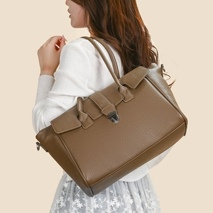 Detail of brown pebble leather tote bag with metallic shield lock and sturdy handles