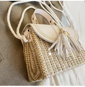 Detail view of woven straw bag with leather flap, tassels and rope shoulder strap
