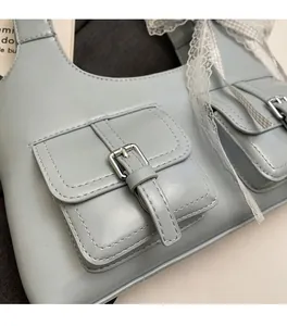 Detail of light blue PU leather bag with silver buckles and a white lace ribbon accessory