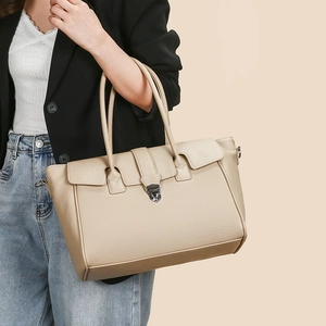 Close-up of beige lychee grain leather tote bag featuring a silver metal buckle lock