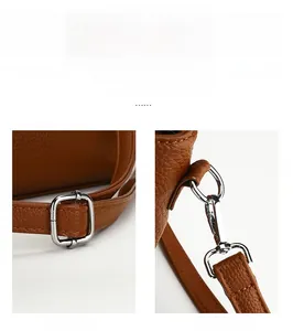 Detail of silver metal adjustment buckle and detachable hook on brown litchi leather bag