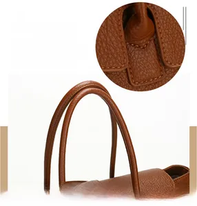 Detail of brown litchi pattern leather tote bag handles and precision stitching