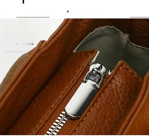 Detail of smooth silver zipper and lychee grain brown leather on tote bag