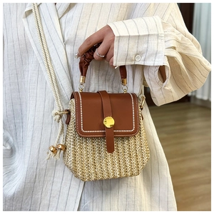 Dettaglio della borsa in paglia intrecciata beige con patta in pelle marrone e fibbia dorata