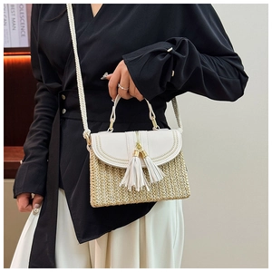 Detail of straw woven bag with white leather flap, gold chain and long tassels
