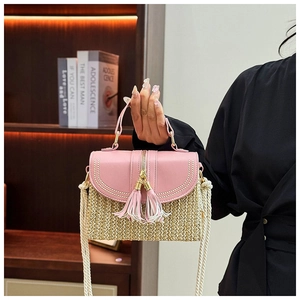Detail of pink leather flap and straw texture with decorative tassels on a tote bag