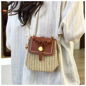 Dettaglio borsa a tracolla in paglia intrecciata beige con patta in pelle marrone e fibbia