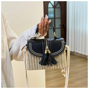 Detail of woven straw bag with black leather flap, golden studs, and rope shoulder strap
