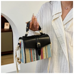 Detail of colorful woven straw bag with black leather flap and thick rope strap