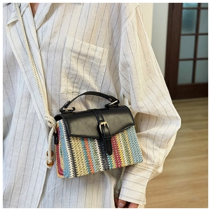 Detail of colorful striped straw bag featuring black leather flap and beaded rope strap