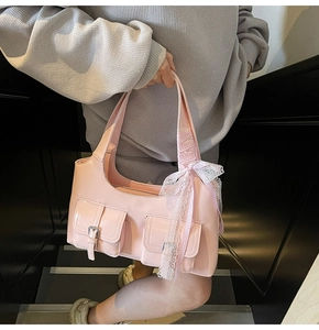 Pink shoulder bag detail showing silver buckle pockets and white lace bow decoration
