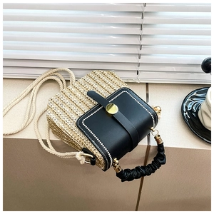 Detail of woven straw crossbody bag with black leather flap and golden metal clasp