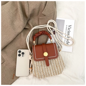 Top view of woven straw crossbody bag with leather flap on a stylish brown blazer