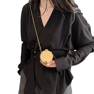 Chic mini round gold metal crossbody bag with chain strap shown on a model