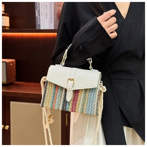 Detail of color-block straw woven bag featuring a white leather flap and golden clasp