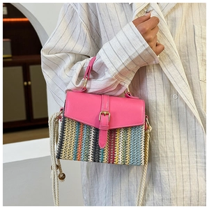 Close-up of color-block woven straw bag with pink leather flap and rope shoulder strap
