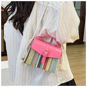 Detail of colorful woven straw bag with pink leather trim and white rope shoulder strap