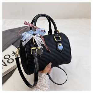 Détail du sac tonneau tressé noir avec rubans à carreaux et finitions en dentelle